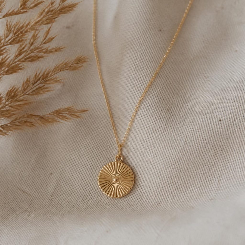 Delicate gold pendant necklace laid flat, a minimalist capsule collection piece