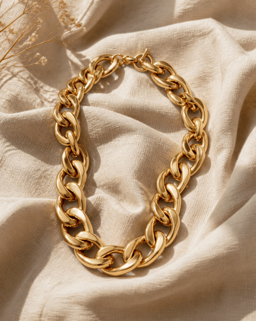 A bold gold chunky chain necklace laid flat on neutral linen
